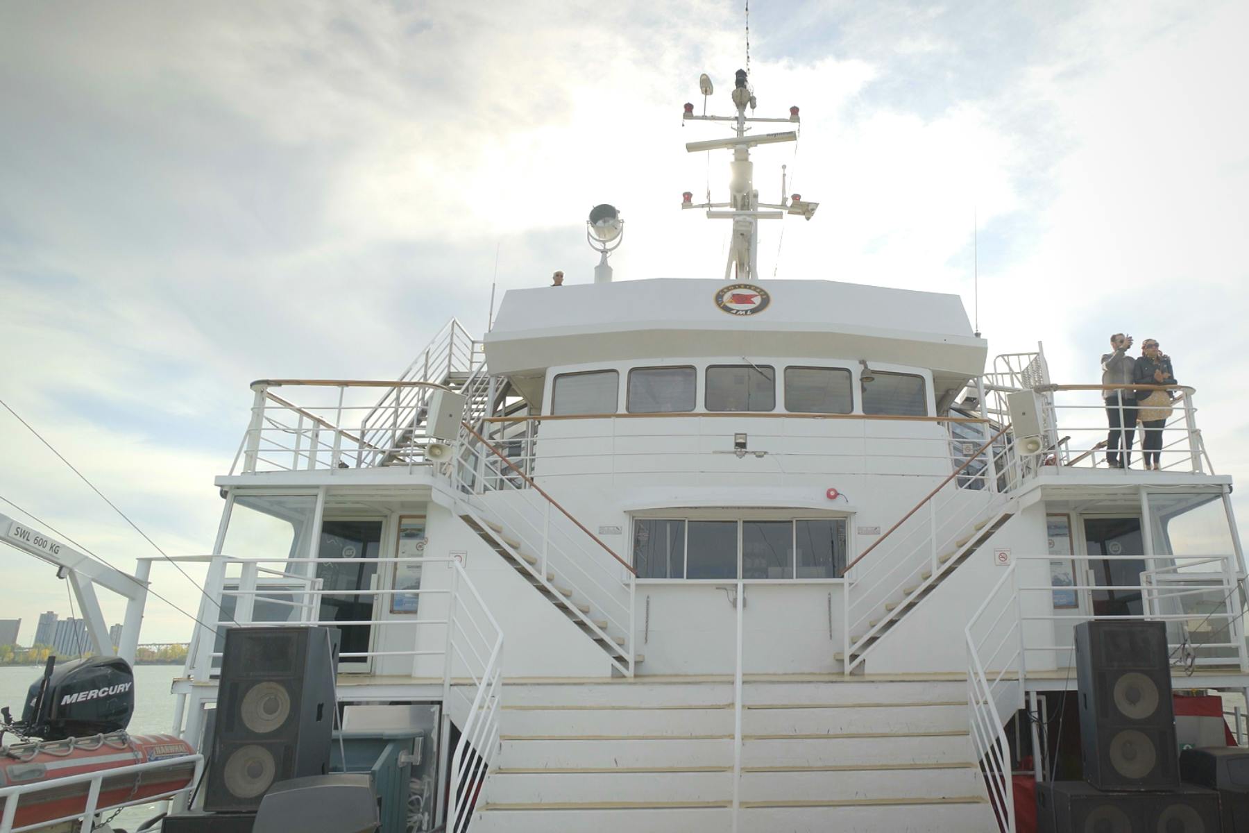 一艘船的上层甲板有通往小木屋的楼梯和可见的结构，如天线和灯光。 云层分散的天空。