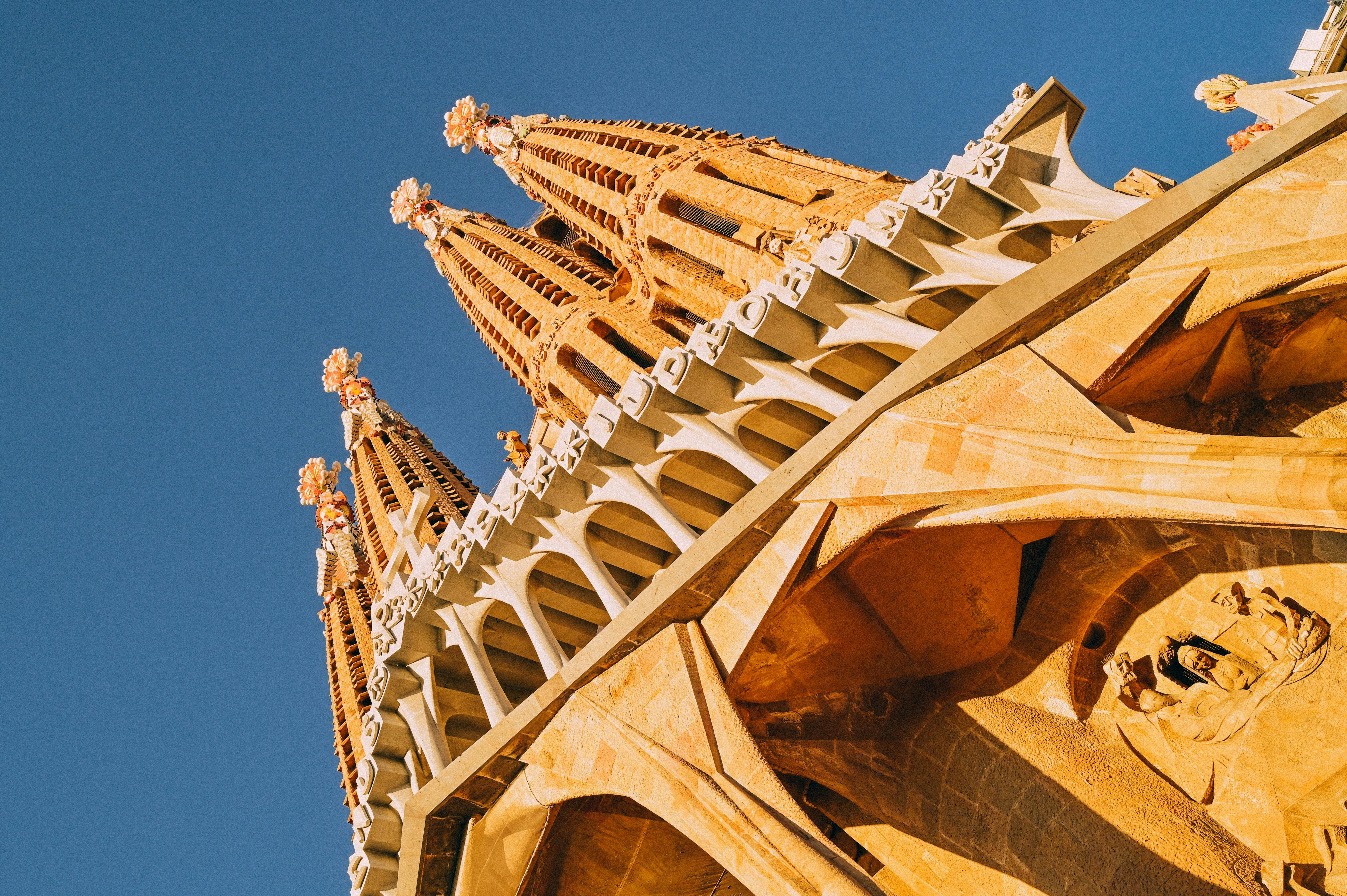 Upward view of the intricate spires and architectural details of a cathedral facade under a clear blue sky.