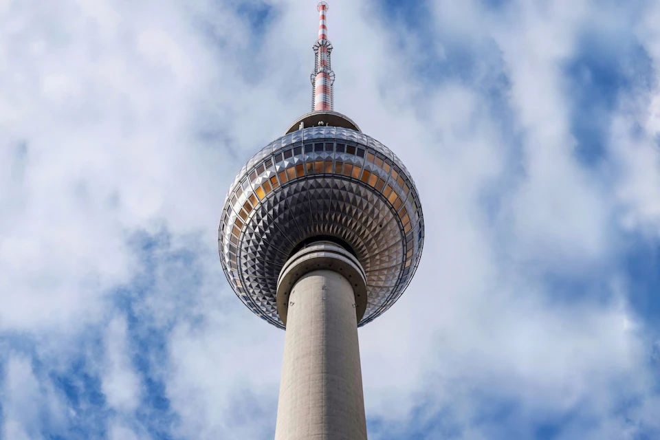 A tall telecommunications tower with a spherical observation deck, viewed against a cloudy sky.