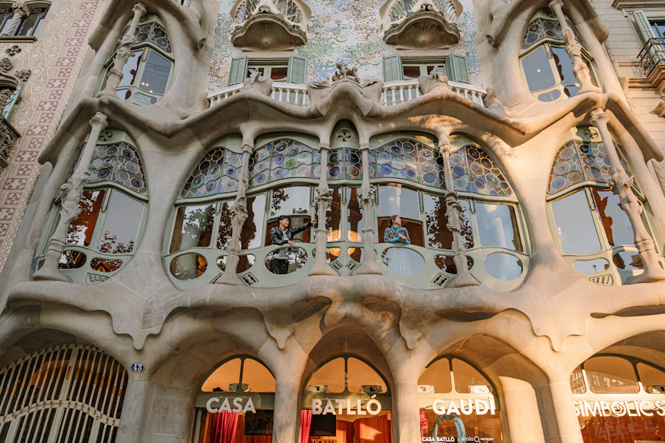 The facade of Casa Batlló, a building designed by Antoni Gaudí, with colorful windows, organic shapes, and decorative details.