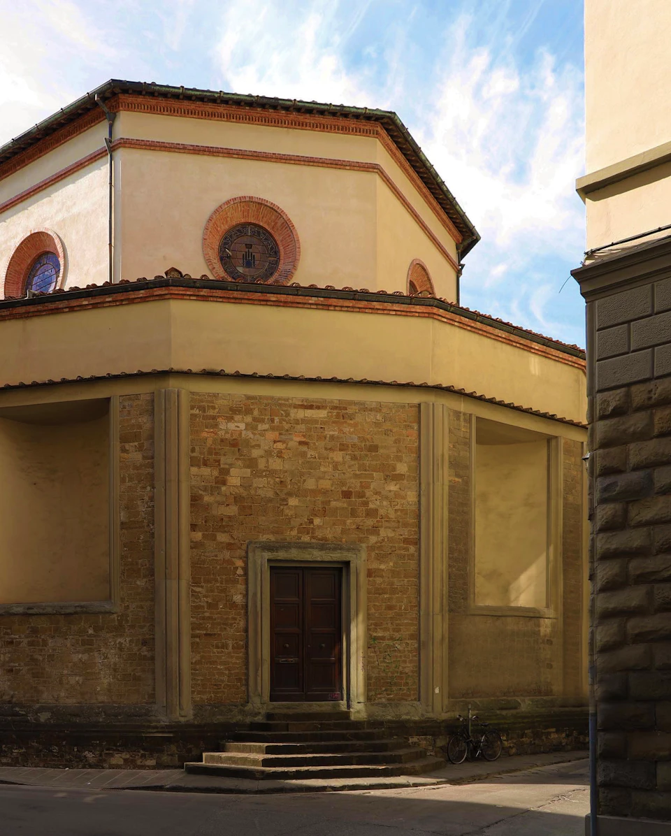 A historic building with an octagonal upper section, round windows with decorative medallions, and a closed wooden door at ground level.