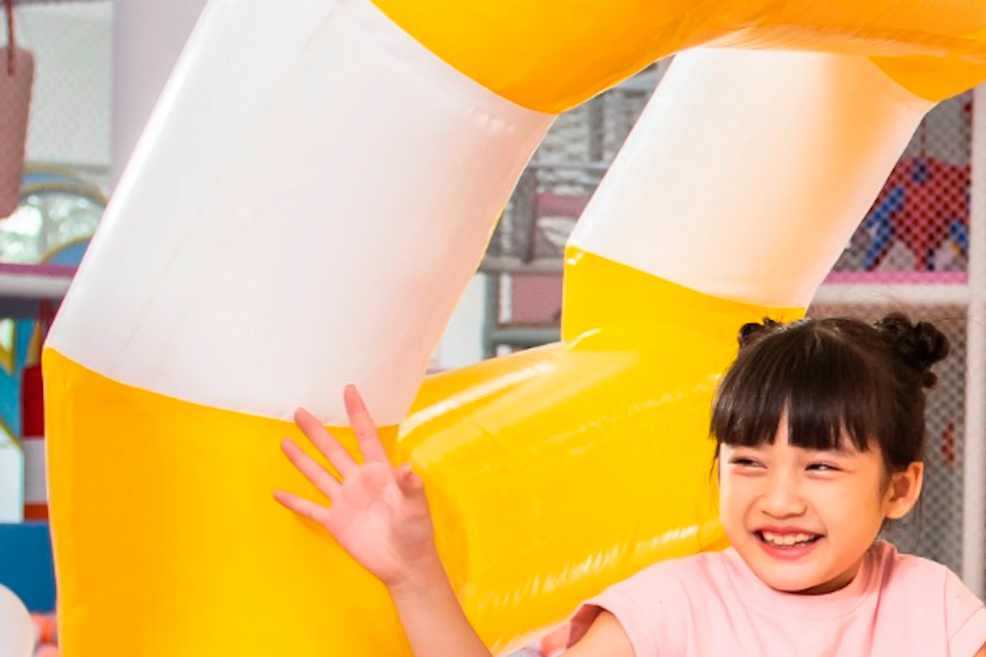 A family with two children playing in a colorful indoor ball pit with an inflatable yellow and white ring.