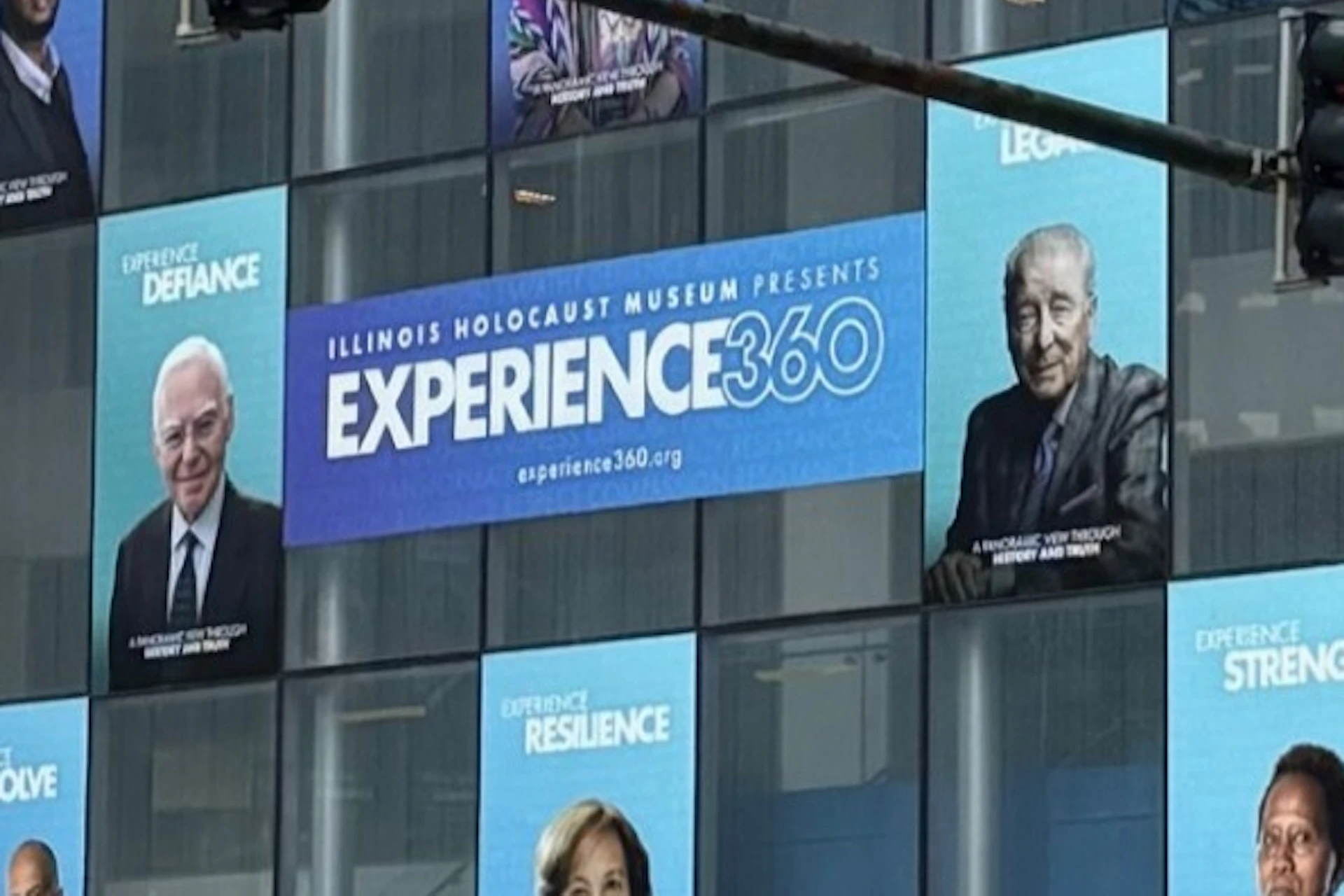 A building facade displaying posters for an exhibition titled "Experience 360," featuring portraits and inspirational words.