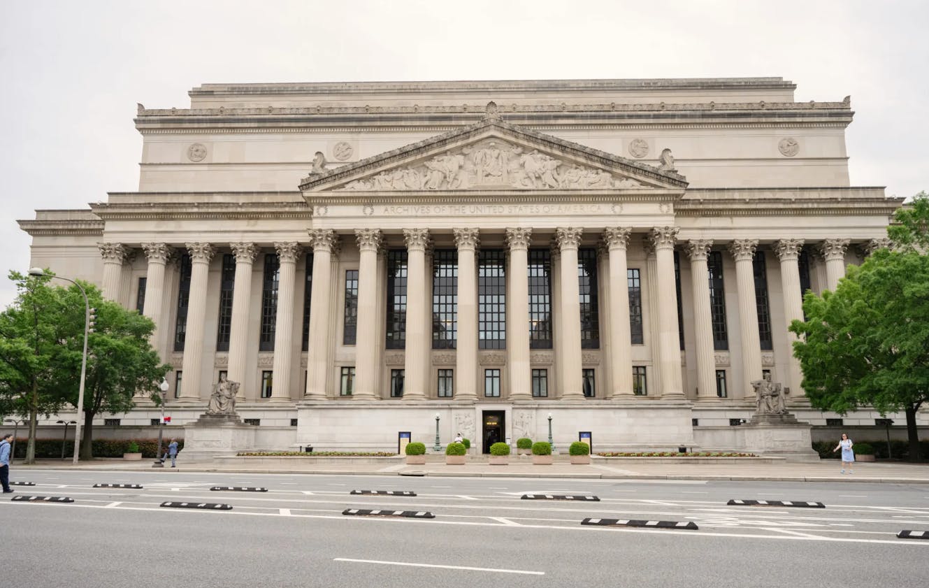 一栋新古典主义风格的大型建筑，高柱、精心设计的饰边和中央入口，可从街对面观赏。