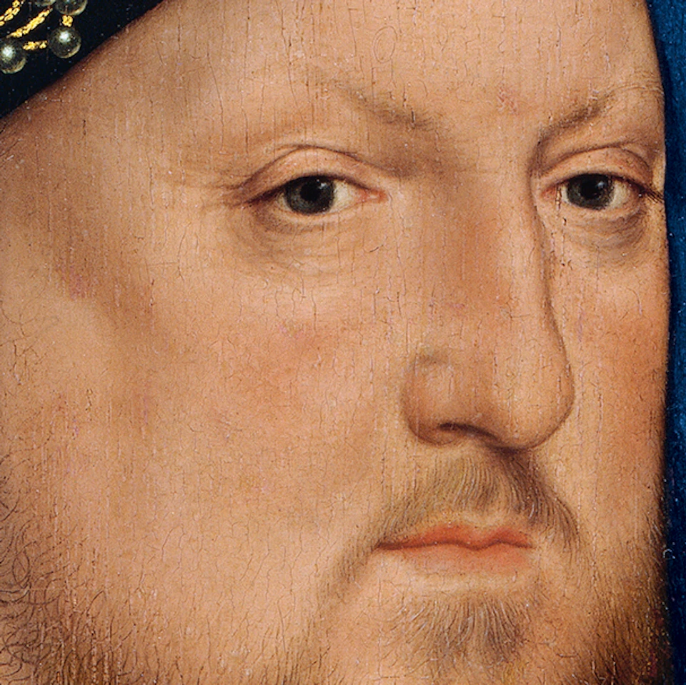 A man in regal attire with a beard and flat hat adorned with gold designs, set against a blue background.