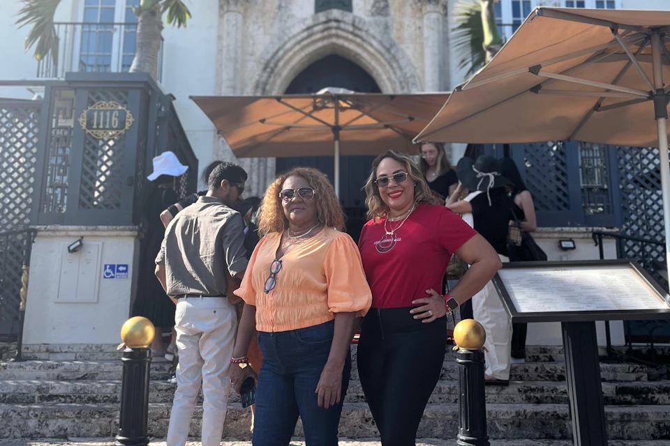 Two ladies pose for a photo in front of the Versace Mansion.