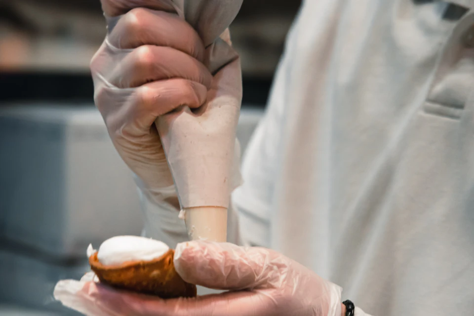 Termini cannoli being filled by hand