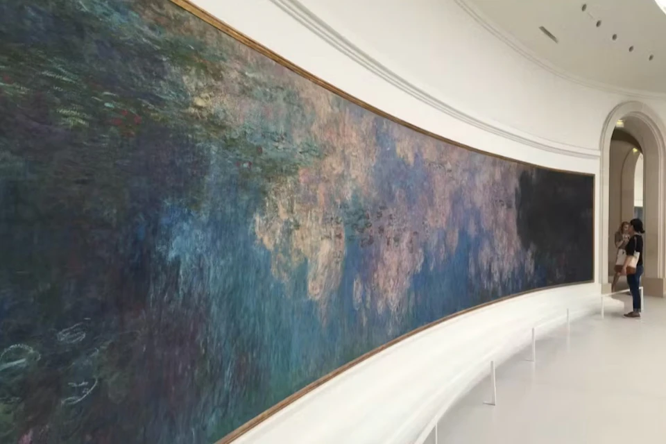 A large wall-mounted painting featuring an abstract water lily scene in a museum gallery with curved benches below.