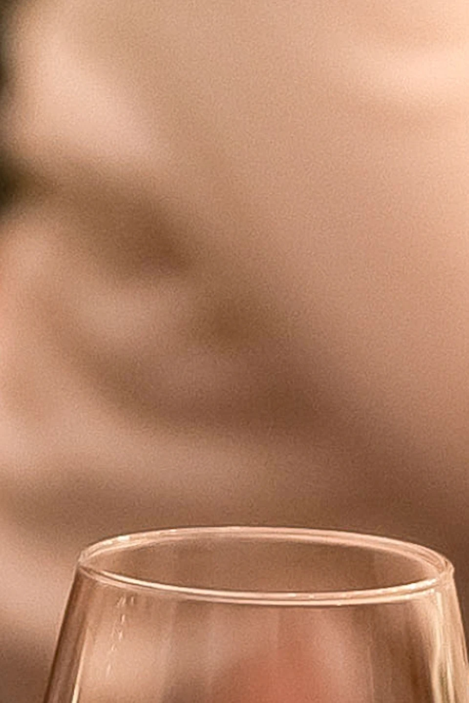 A dining table with glasses, including one with champagne, and a blurry bottle in the foreground.