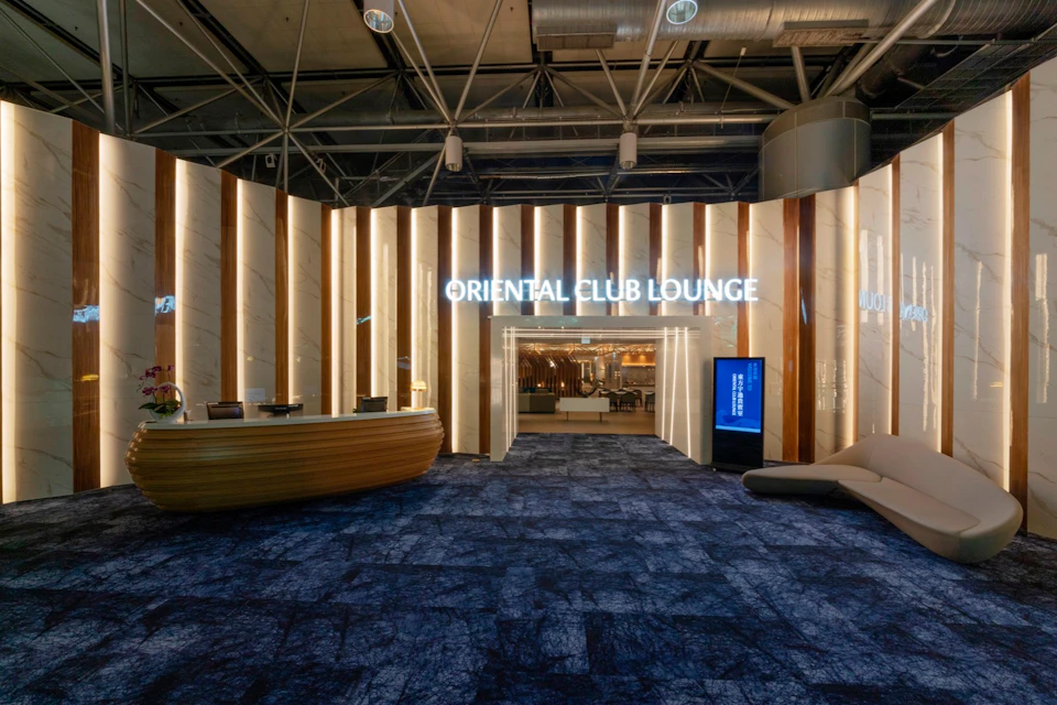 Entrance to the Oriental Club Lounge with illuminated sign, a reception desk, and modern interior design elements.