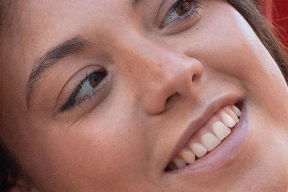 Young woman smiling while taking a selfie on an open-top bus with trees visible in the background.