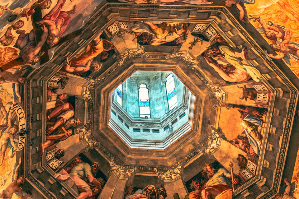 View of a decorated domed ceiling with intricate paintings around an octagonal skylight, revealing part of a building through the window.