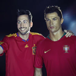 En man i en röd sporttröja tar en selfie med en naturtrogen vaxskulptur av en fotbollsspelare i en röd tröja.