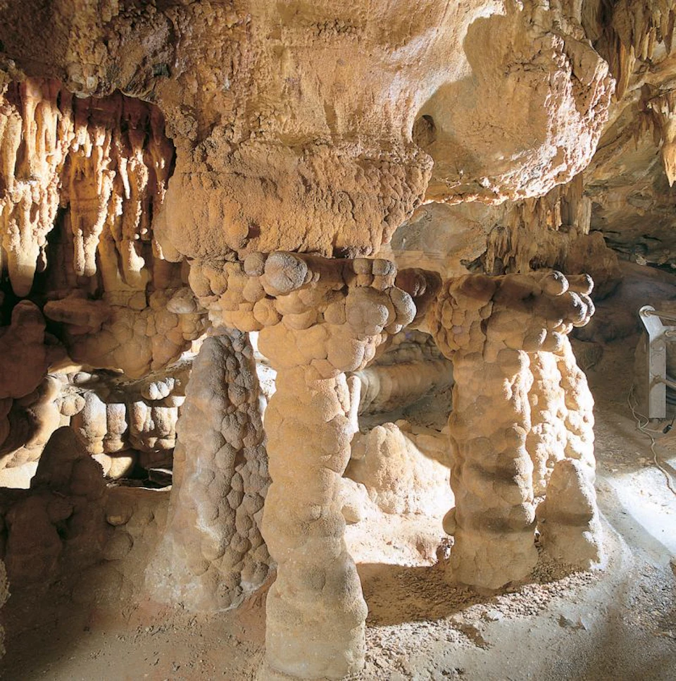 Natural limestone cave interior with stalactites hanging from the ceiling and stalagmites rising from the floor.