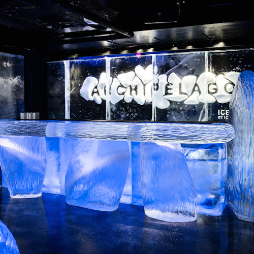 En bar gjord helt av is, med skulpterade ispallar, en bänk och väggar, upplysta av blått ljus. ”Skärgården” är huggen bakom baren.