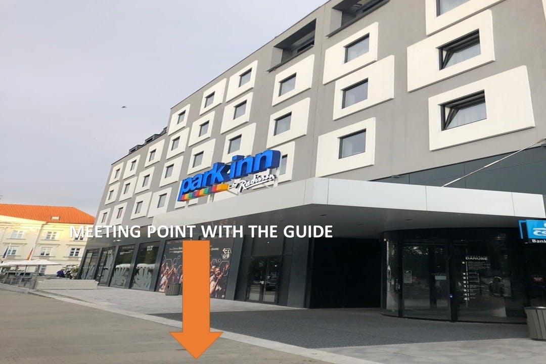Σύγχρονο εξωτερικό του ξενοδοχείου με την πινακίδα "Park Inn by Radisson". Ένα πορτοκαλί βέλος δείχνει σε ένα σημείο συνάντησης στο πεζοδρόμιο κάτω από την πινακίδα.