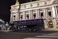 O ônibus Toqué Champs-Elysées em frente à Ópera de Paris à noite