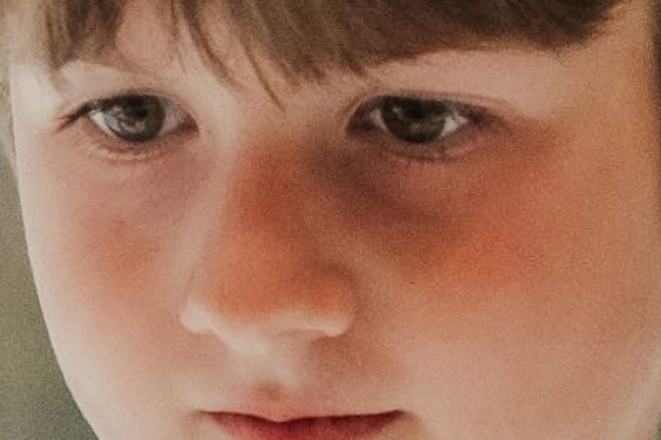 Young boy in a striped shirt looking intently at two glass display domes in a museum-like setting.