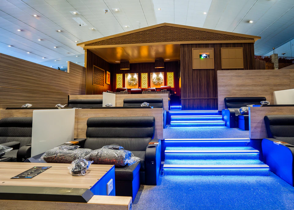 A stylish lounge with recliner seats, blue-lit stairs, and a wooden cabin-style raised area with decorative art on the walls.
