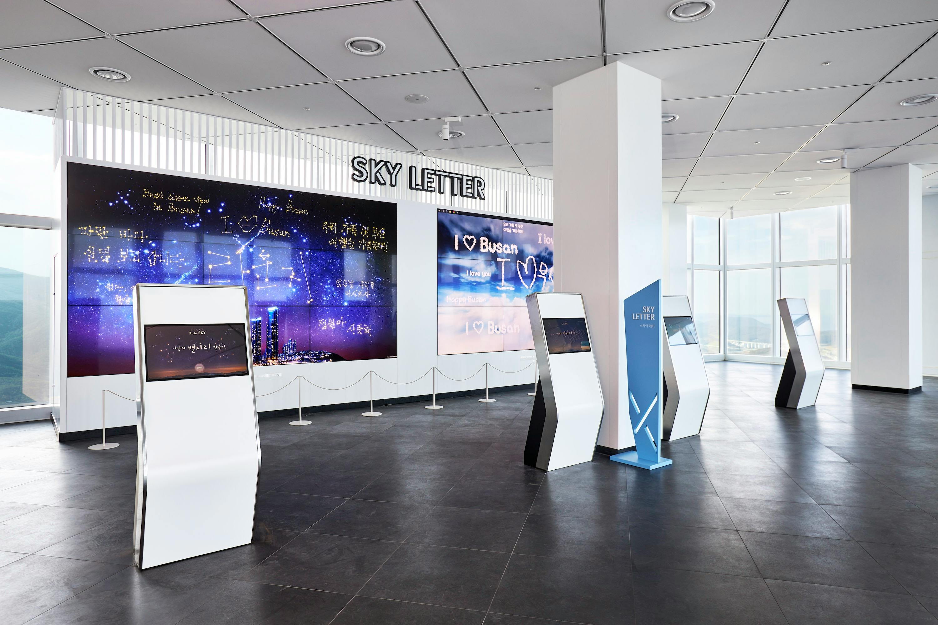 An indoor exhibit area labeled 'Sky Letter' with interactive kiosks and illuminated wall displays showing inscriptions.