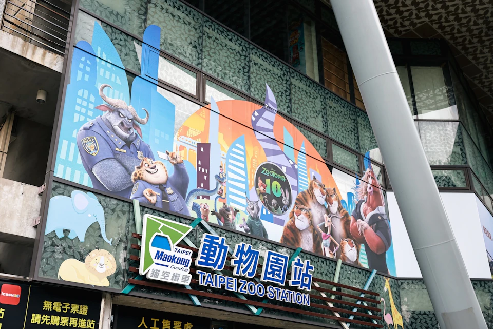 The Taipei Zoo station entrance features colorful Zootopia-themed artwork and signage in Chinese and English.