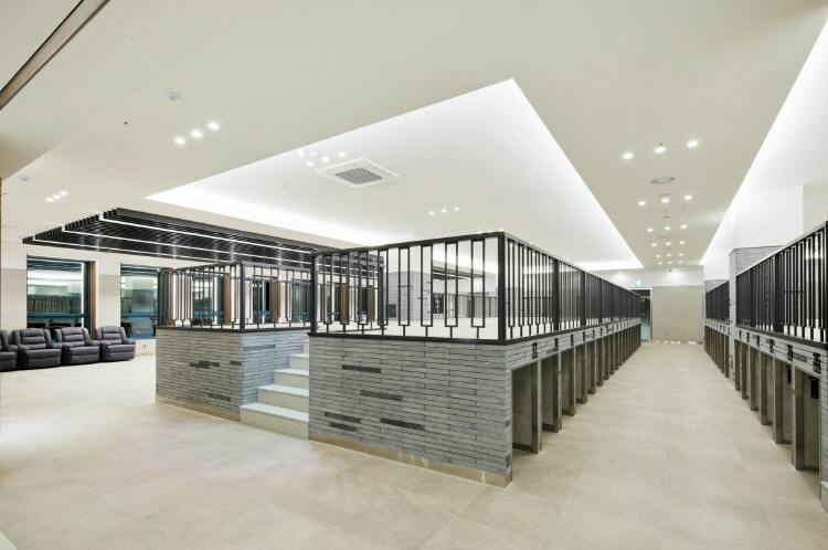 A modern interior with a raised platform surrounded by black railings, steps leading up, and bright ceiling lights.