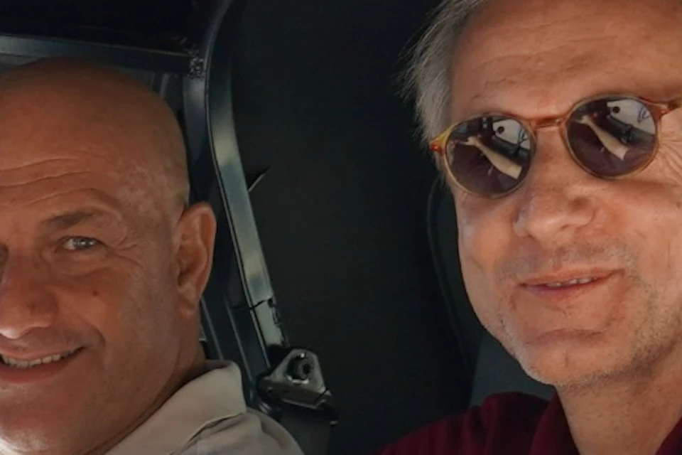 Two men smiling and sitting in a small electric car with "Discover Málaga" and "App Málaga Tour" decals.