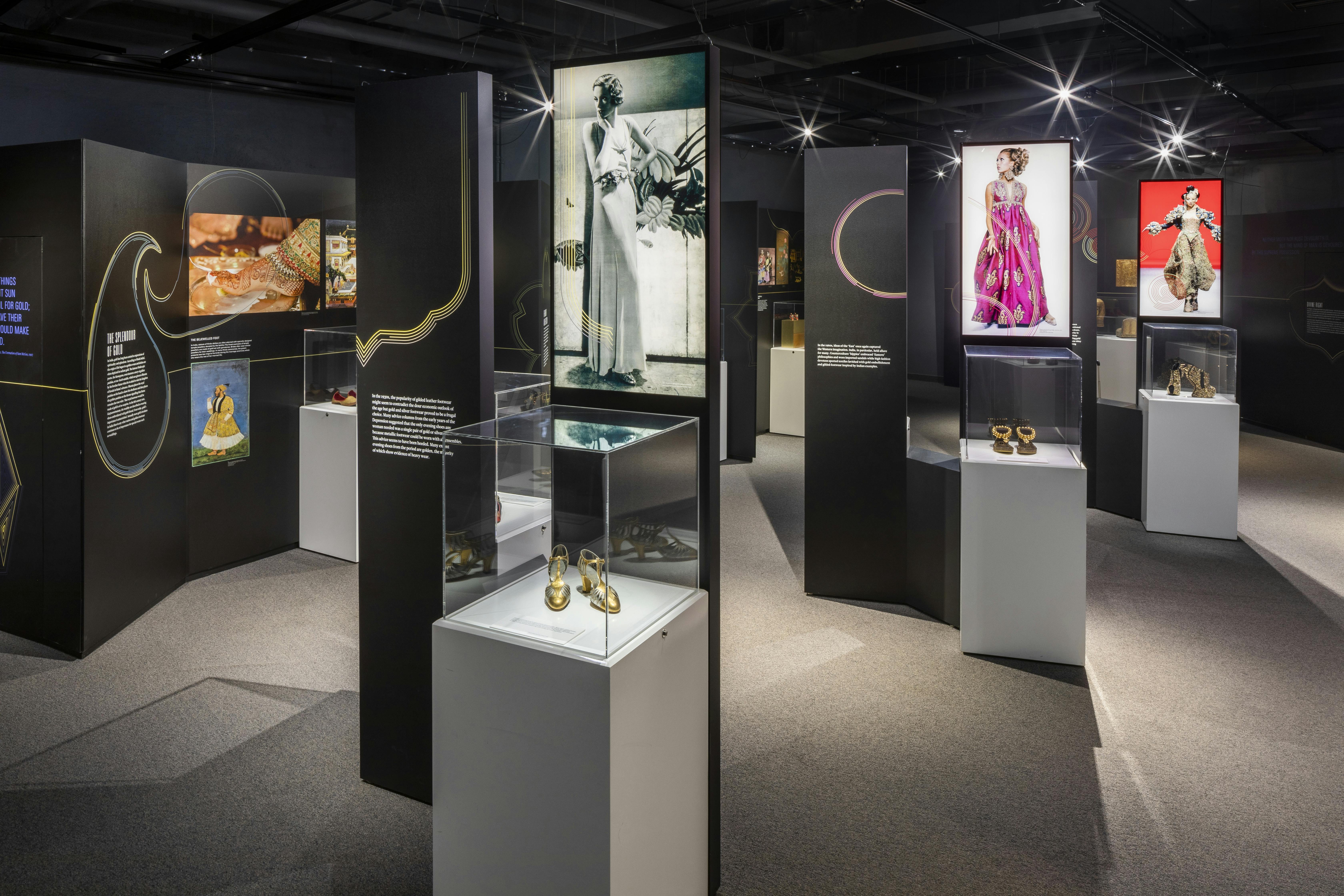 Et museumsudstilling har fotografier, beskrivende paneler og forskellige artefakter, der vises i glaskasser på piedestaler.