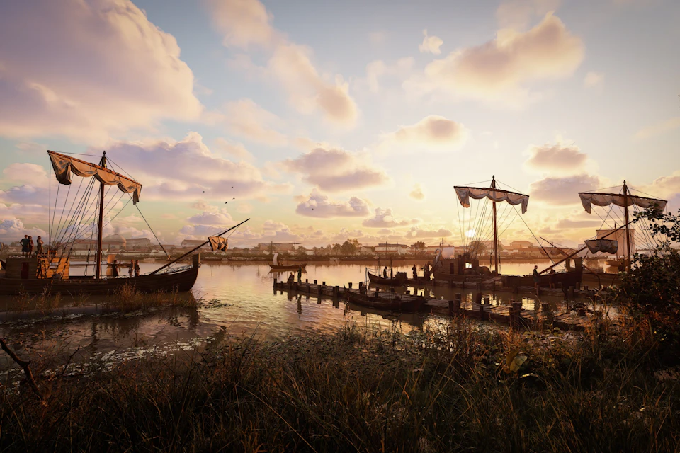 A serene riverside scene at sunset with wooden ships docked and people on the pier, surrounded by grass and water.