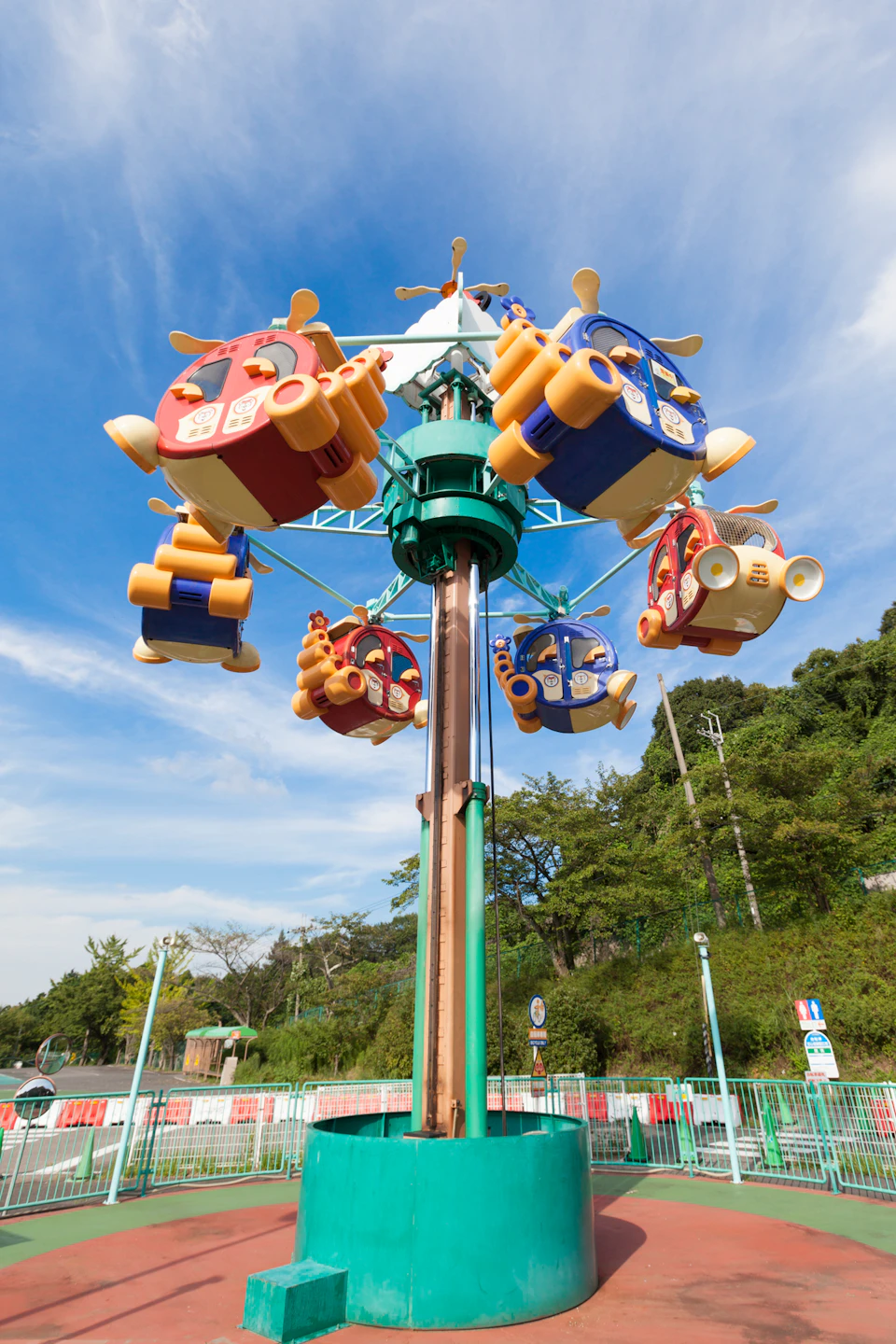 A colorful amusement park ride with car-shaped gondolas suspended on a rotating structure under a clear blue sky.