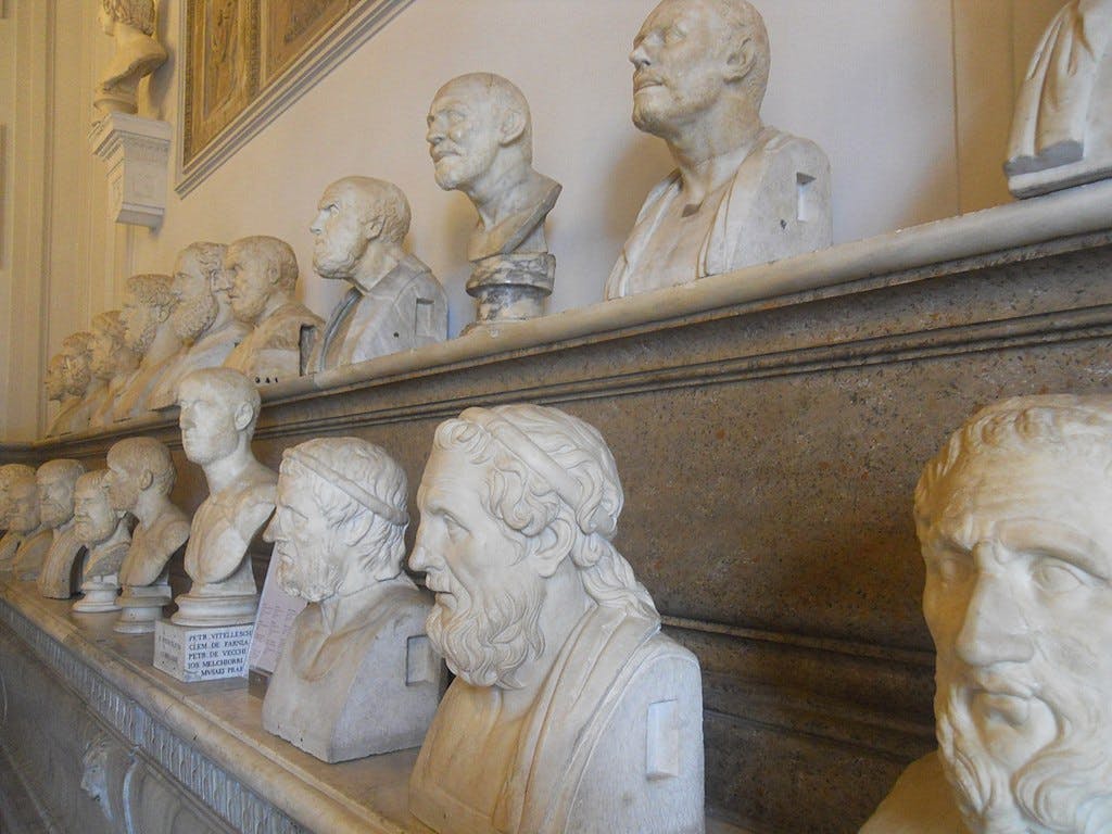 A row of marble busts depicting various historical figures displayed on shelves in a museum setting.