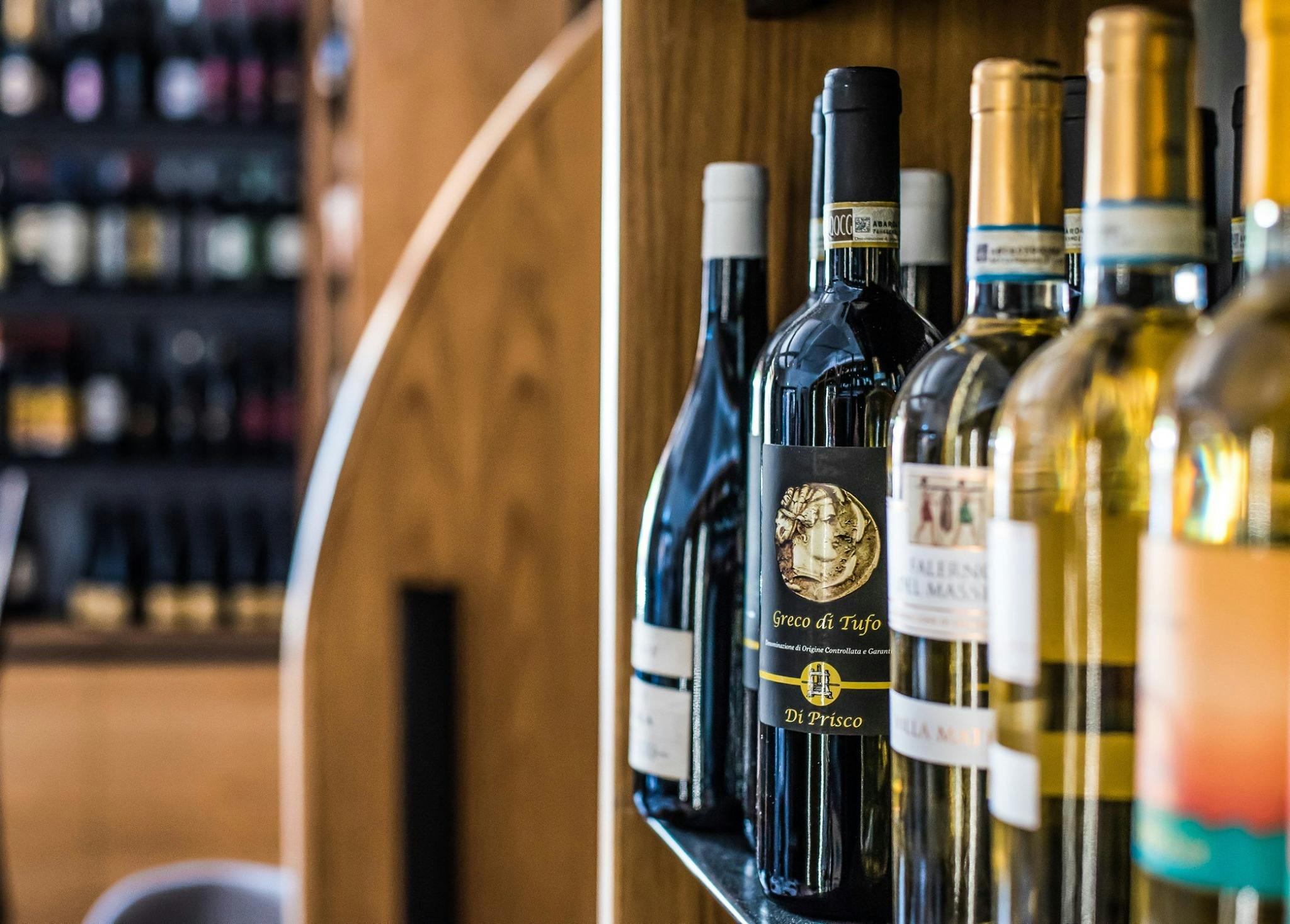 Бутылки вина выставляются на полках в винном магазине на деревянном фоне.