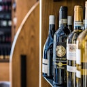 Bottles of wine are displayed on shelves in a wine shop with a wooden backdrop.