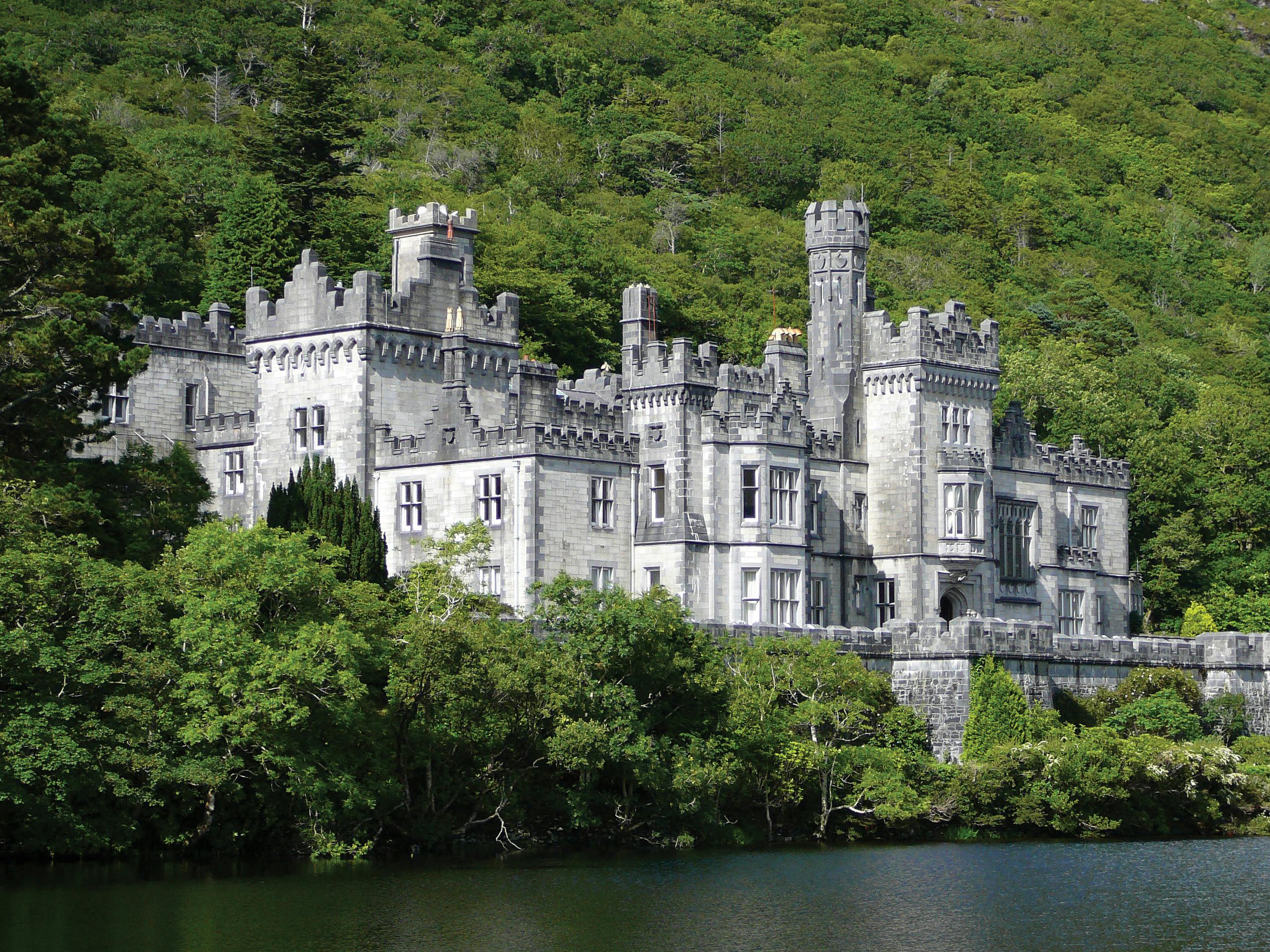 빽빽한 푸른 나무로 둘러싸인 수많은 탑과 화신이 있는 석조 성이 잔잔한 물가에 자리하고 있습니다.