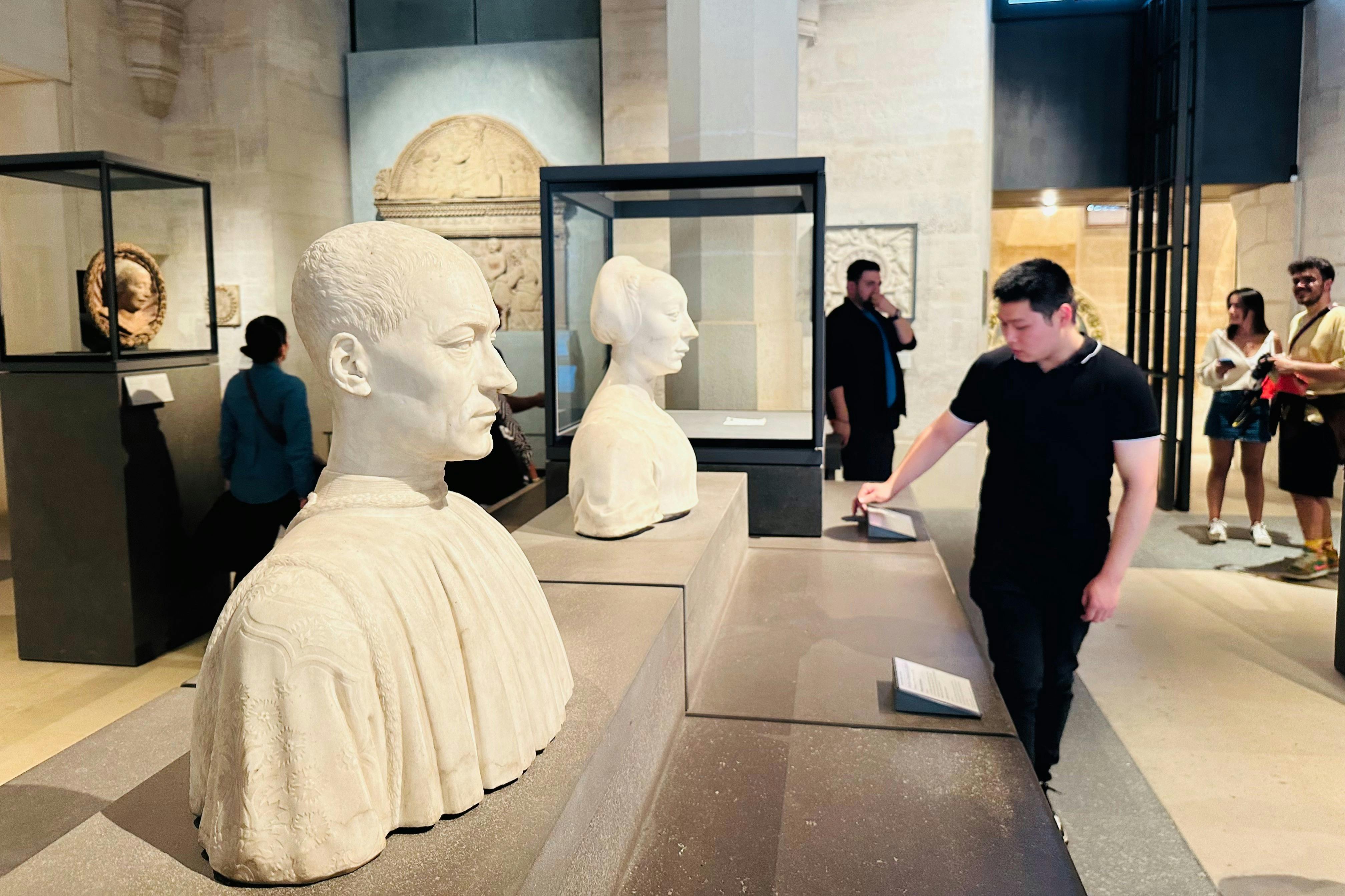 박물관에 전시된 대리석 흉상을 배경으로 두 사람이 전시물을 관찰하고 있습니다.
