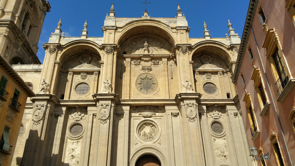 Facade of a historic stone building with ornate architectural details and statues under a clear blue sky.