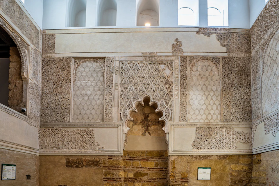A decorative wall with intricate patterns and an arched doorway, showing a blend of architectural styles.