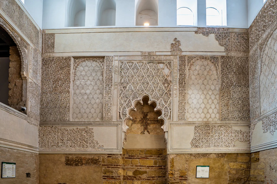 A decorative wall with intricate patterns and an arched doorway, showing a blend of architectural styles.