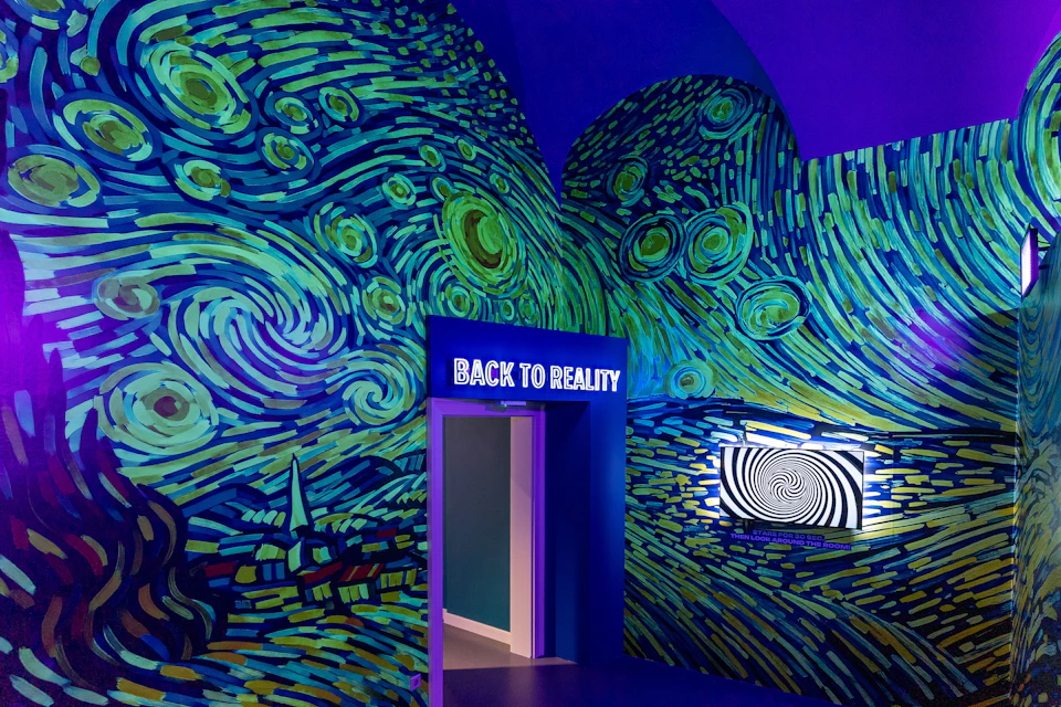A room with walls painted in a Van Gogh-inspired style, a doorway labelled 'Back to Reality,' and a digital art display.