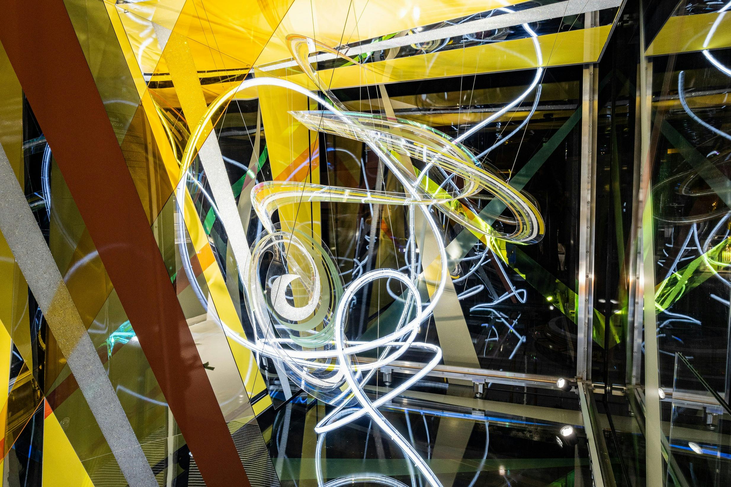 黄色、緑色、茶色の渦巻く白いネオンライトと幾何学模様の抽象的な光のインスタレーション。反射面。