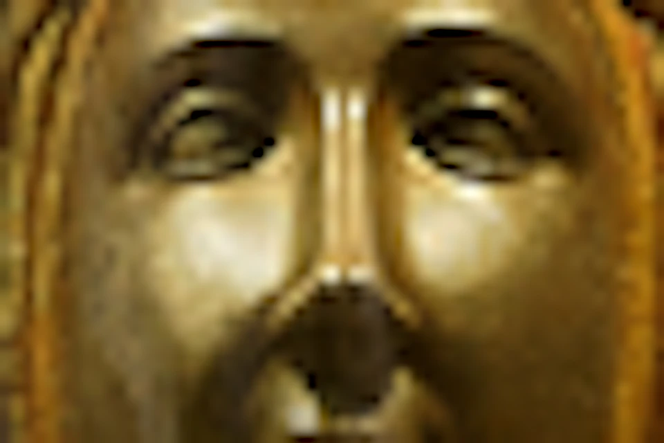 A golden statue of a seated figure with a child, surrounded by intricate metalwork and religious relief carvings.