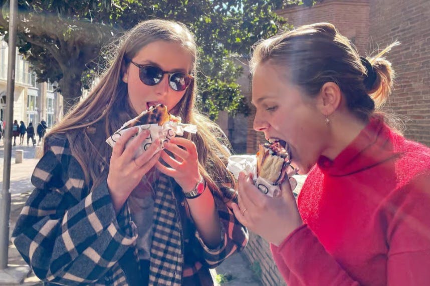 Two women eating sandwiches in the street