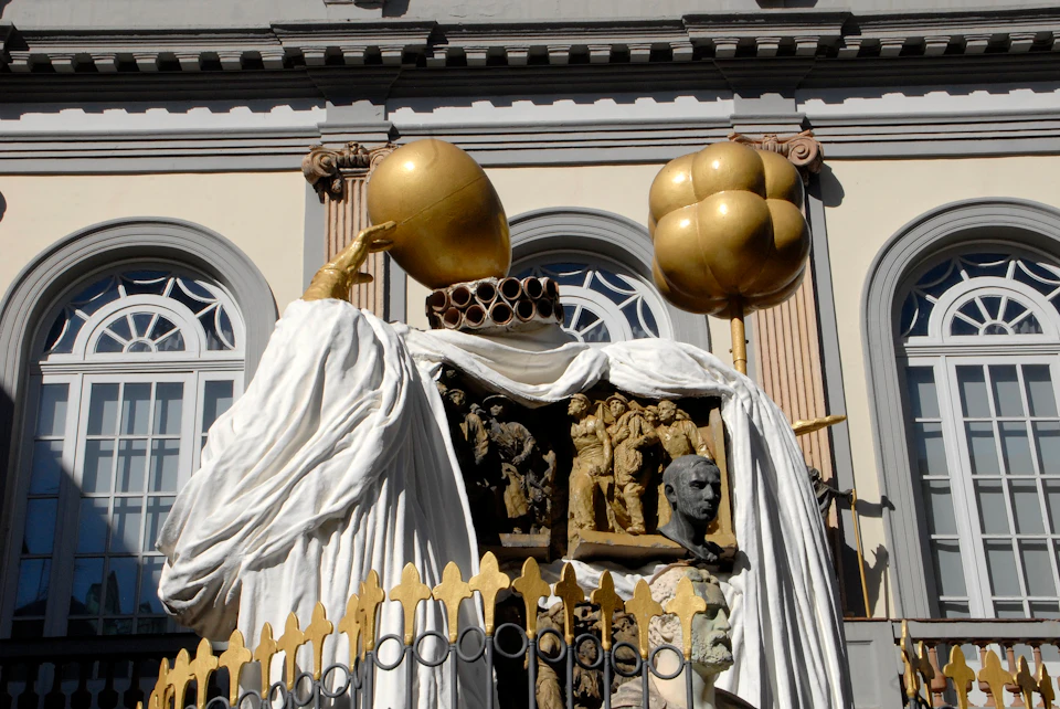Golden sculptures and ornate details on a building façade, featuring white draped figures and intricate carvings.