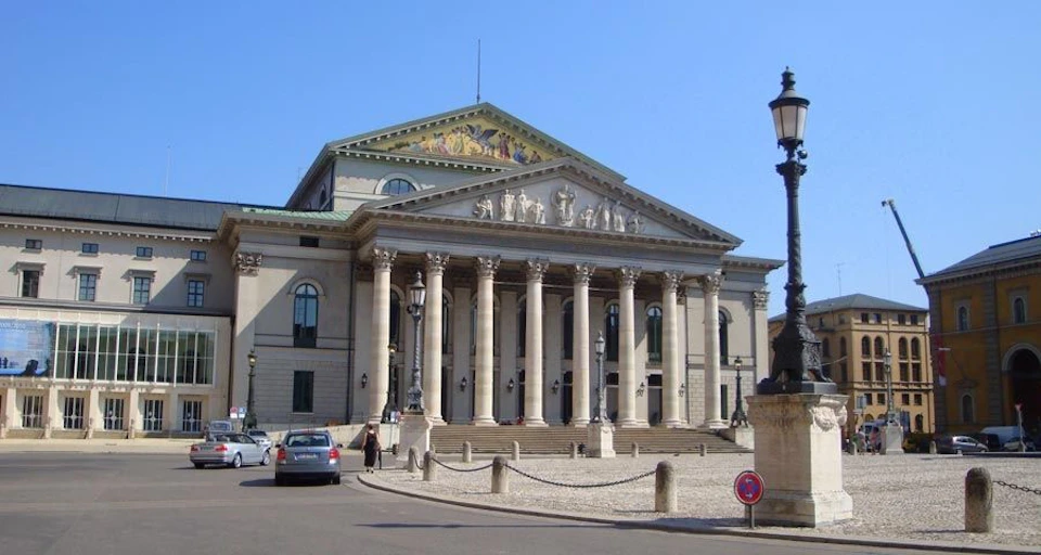 A neoclassical building with a portico supported by columns, featuring intricate sculptures and a triangular pediment with a mural.