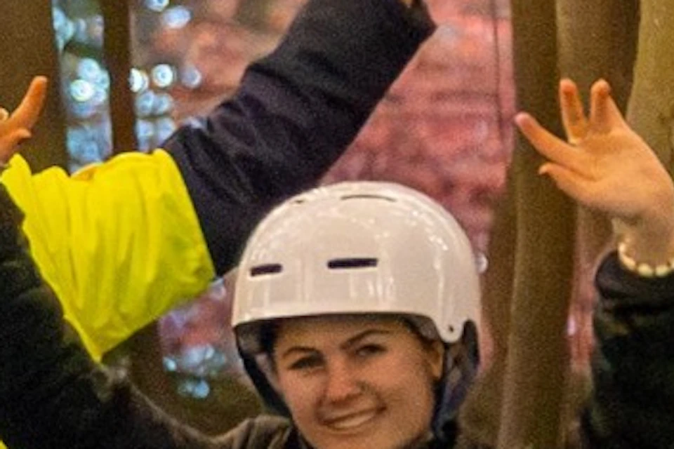 A group of people on Segways in a garden at night, with trees illuminated by strings of lights.