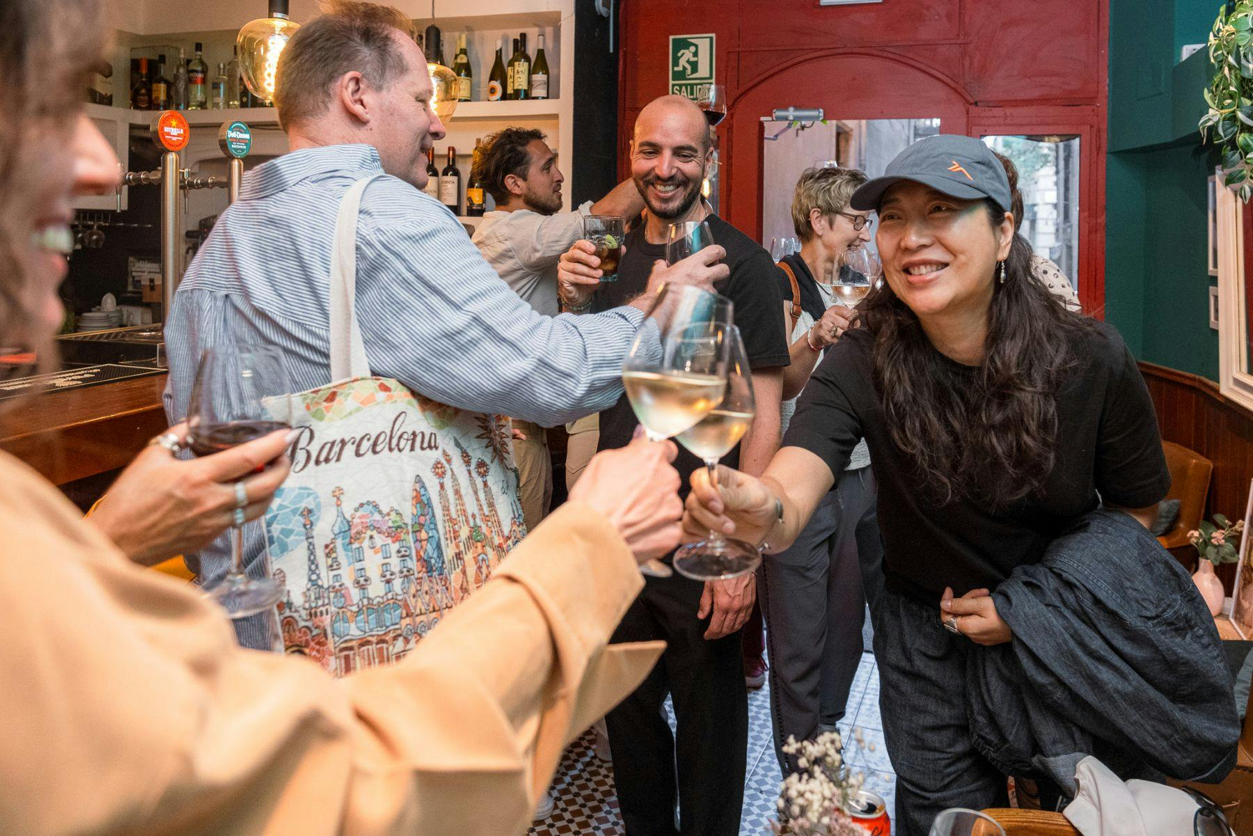 Um grupo de pessoas a socializar e a brindar com copos de vinho num ambiente acolhedor, vibrante e interior.