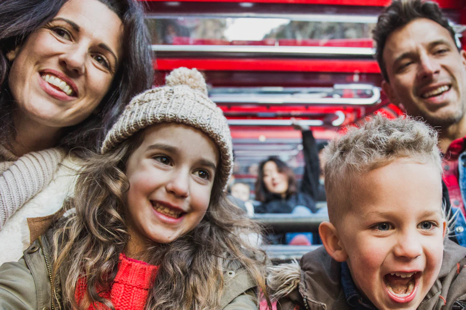 A smiling family of four sits on an amusement ride. The mother and daughter are on the left, the father and son on the right.