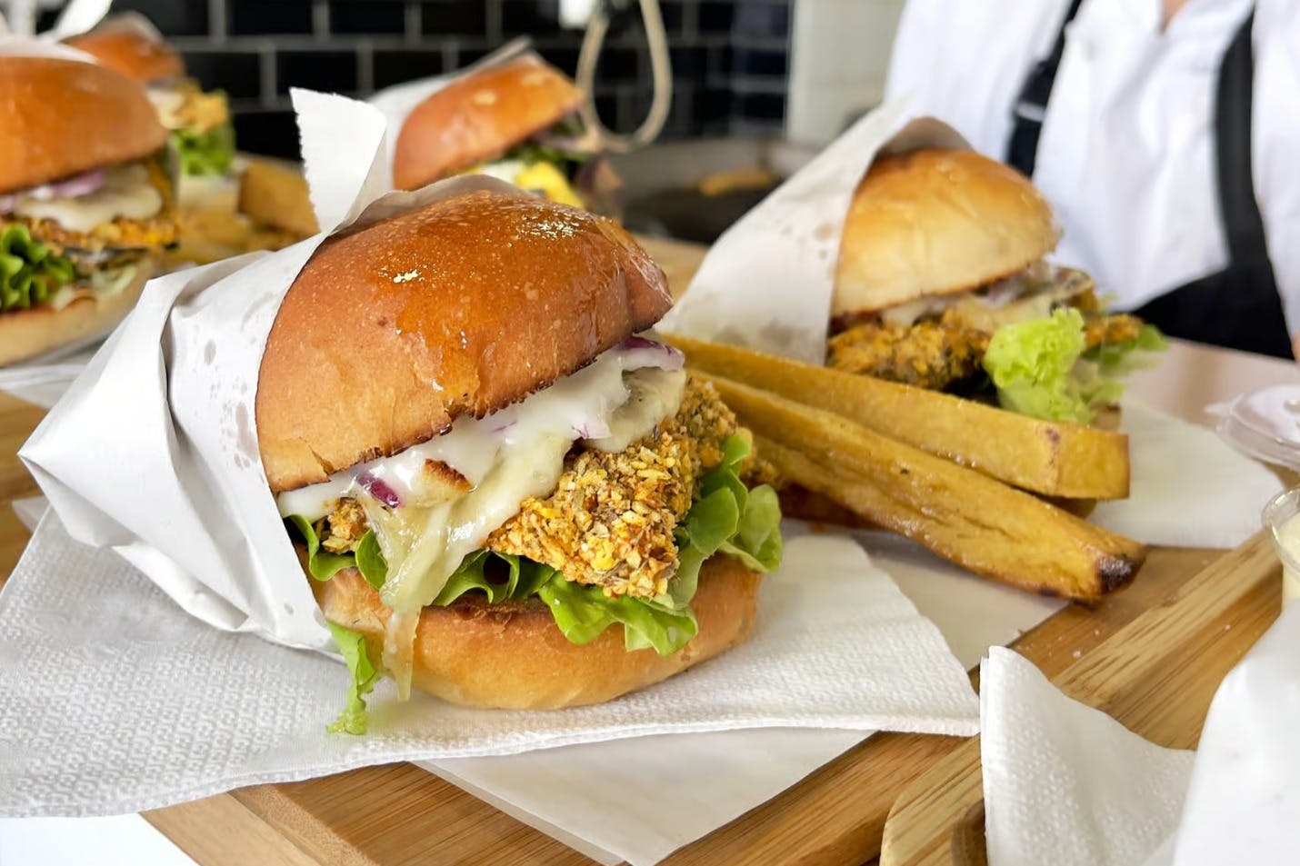 5 burgers placed on a tray in a restaurant and wrapped in paper