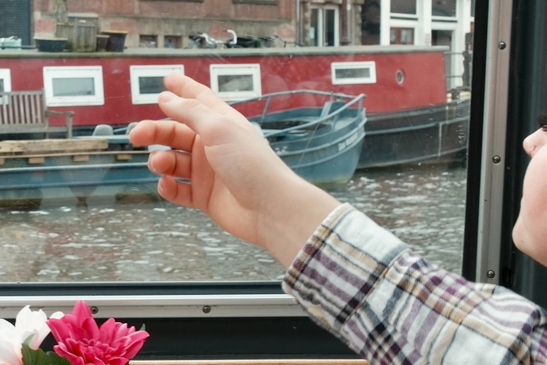 Four people seated at a table in a glass-roofed boat, looking at the canal and buildings outside.