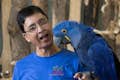 Homem segurando um papagaio arara-azul em sua mão